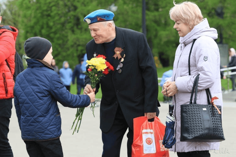 Ветеран ВДВ получает букет цветов от российского ребёнка в Парке Горького (10 мая 2022 года). Фото: Чан Хиеу / ВИА