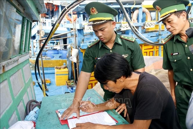 Офицер пограничной службы Цинхая инструктирует рыбаков подписать обязательство не нарушать НРП. (Фото предоставлено TTXVN)